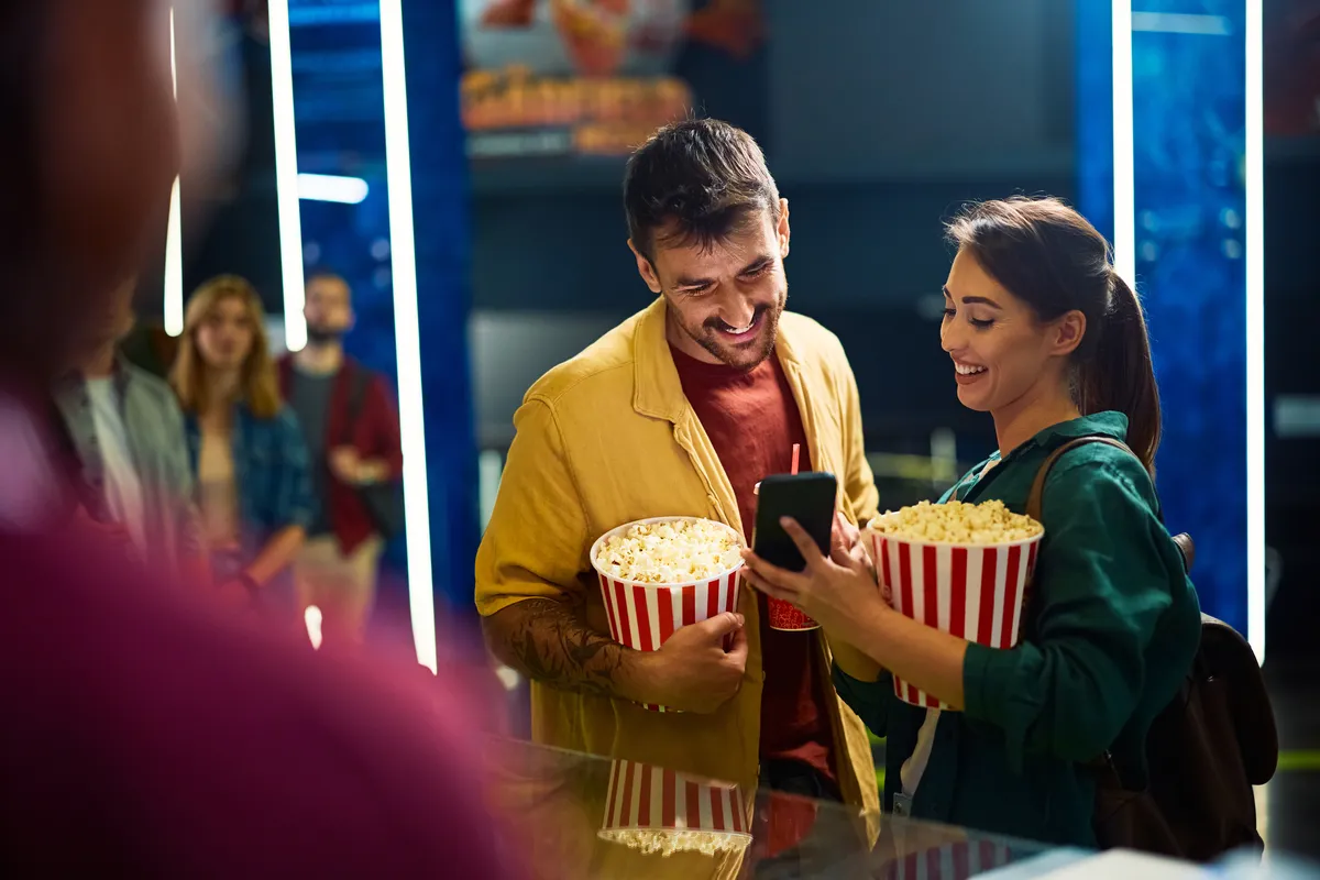 young-happy-couple-using-smart-phone-in-cinema