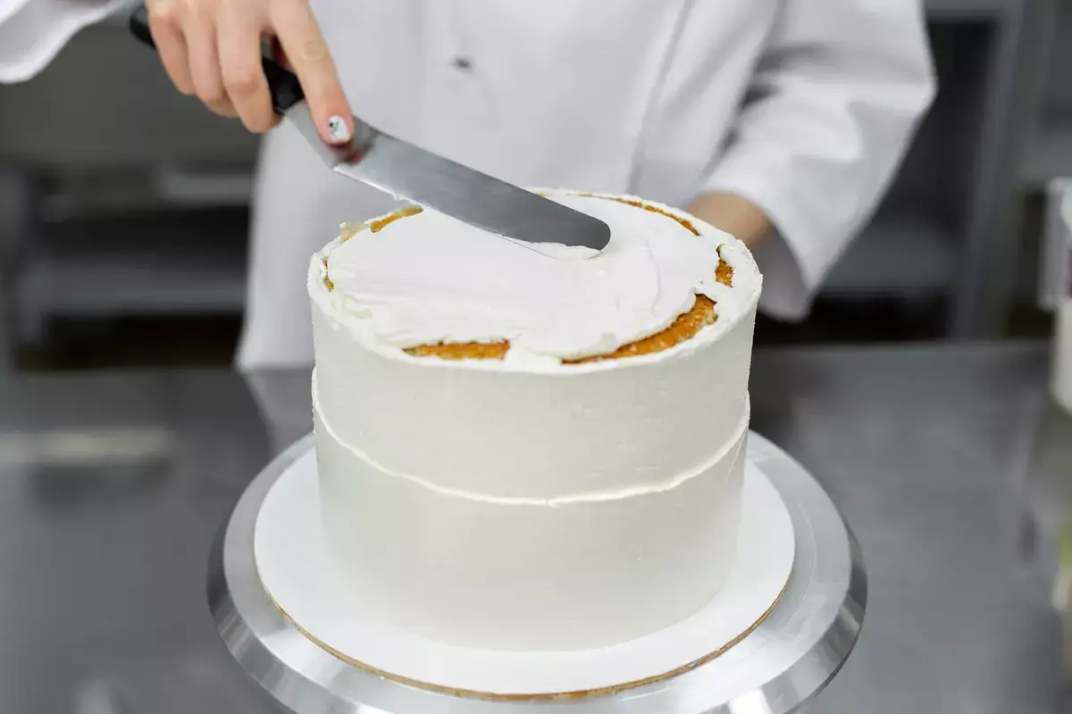y-chef-levels-the-cake-with-cream.webp