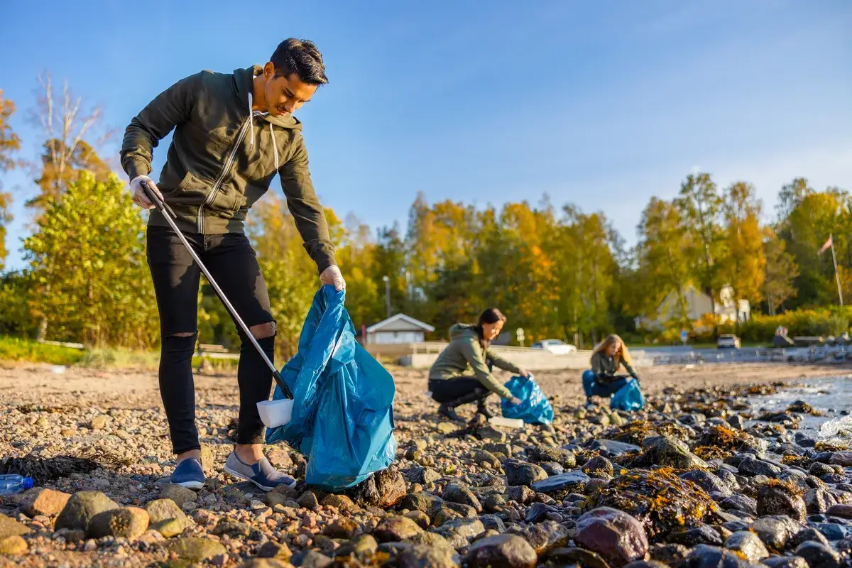 man-cleaning-beach-with-volunteers