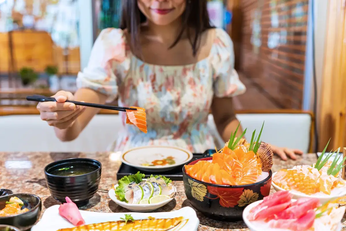 young-asian-woman-eating-sashimi-set-in-japanese