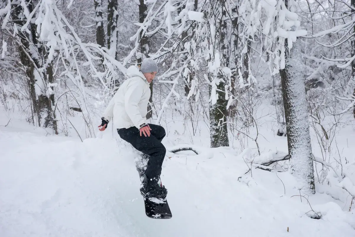 young-man-snowboarding-past-snowy-trees