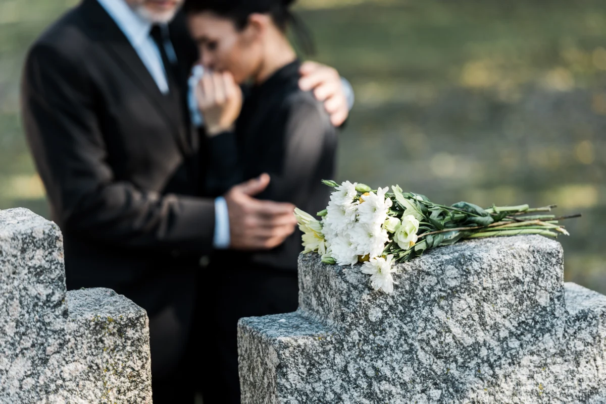 mourning-couple-at-grave-with-flowers